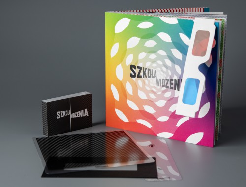 Okładka książki „Szkoła widzenia” Na zdjęciu książka „Szkoła widzenia” oraz leżące obok niej akcesoria - dodatki do wydania: okulary 3D, flip-book, folie pomocnicze