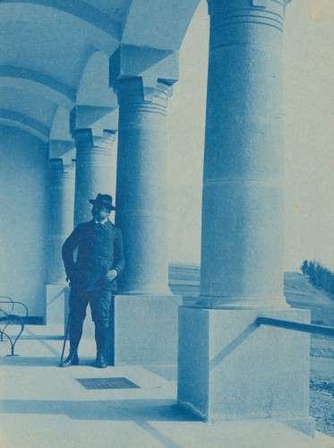 Mężczyzna stojący w kolumnowej loggi pałacu.