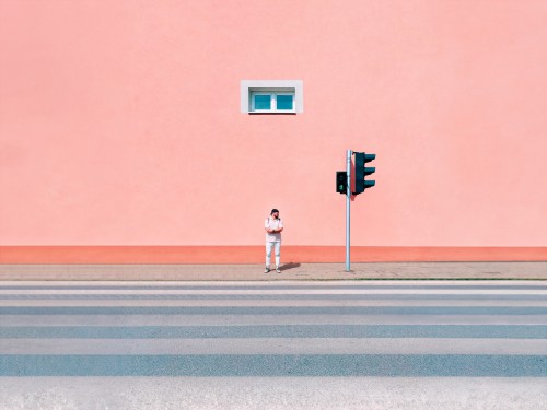 Mężczyzna stojący w oddali na tle różowej ściany. 